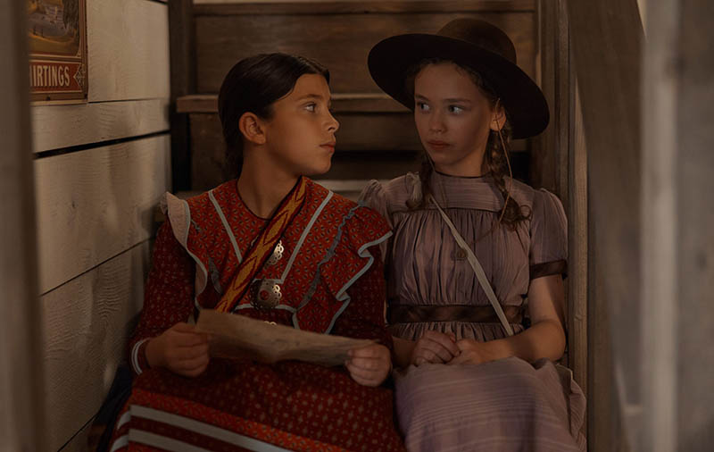 "Two girls sit together on the stairs. "